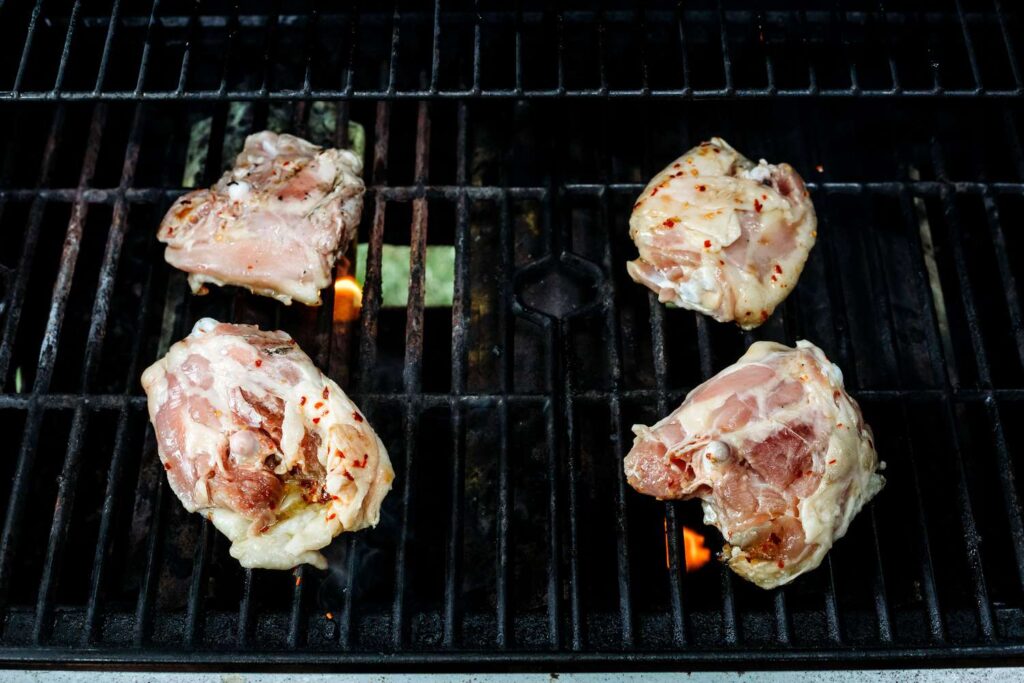 Place the chicken thighs skin-side down on the grill.