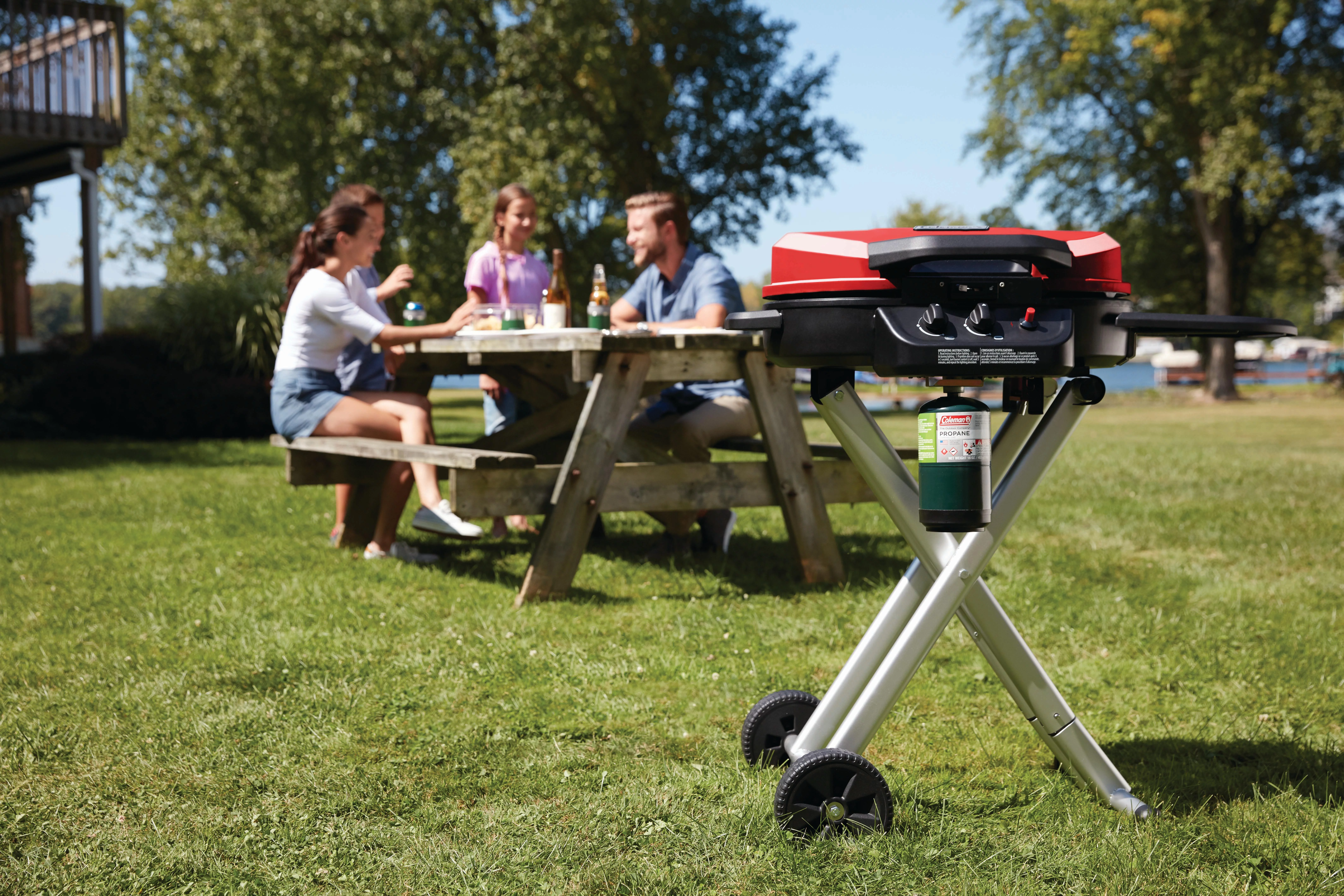 Portable Coleman BBQ with people in the background