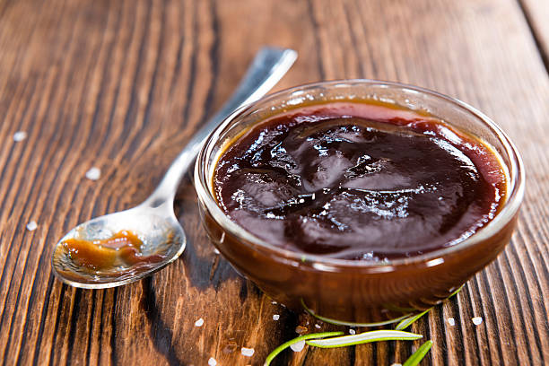 Chocolate Chipotle BBQ Sauce with Tomatoes, Smoked Salt and fresh Herbs (on rustic wooden background)